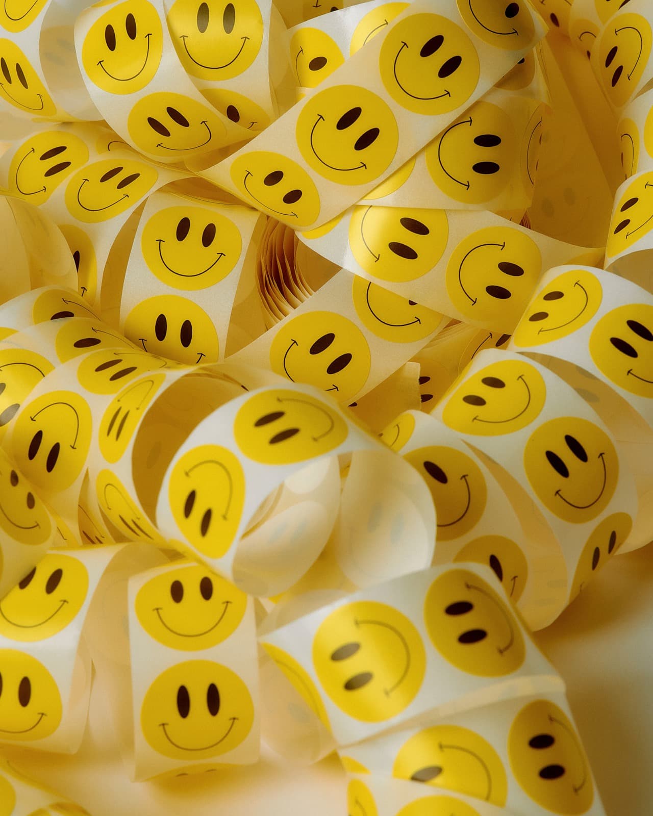 Bandes d'autocollants ronds à visage souriant qui s'enroulent, empilées en vrac les unes sur les autres